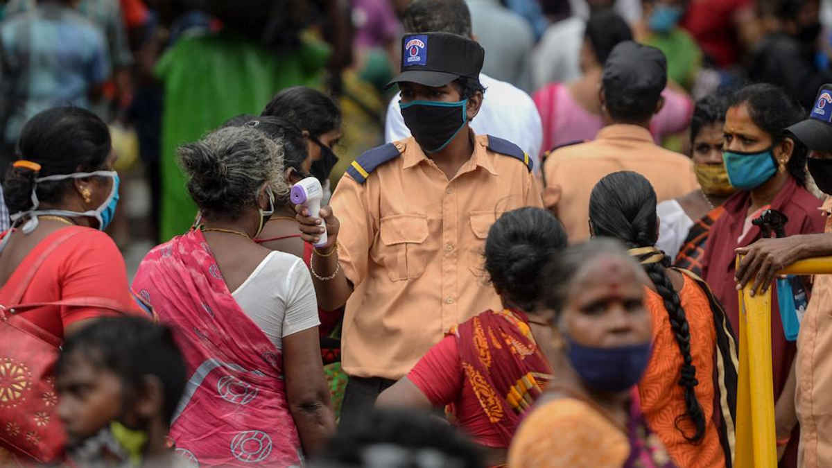 A security personnel checks the temperature of a woman 